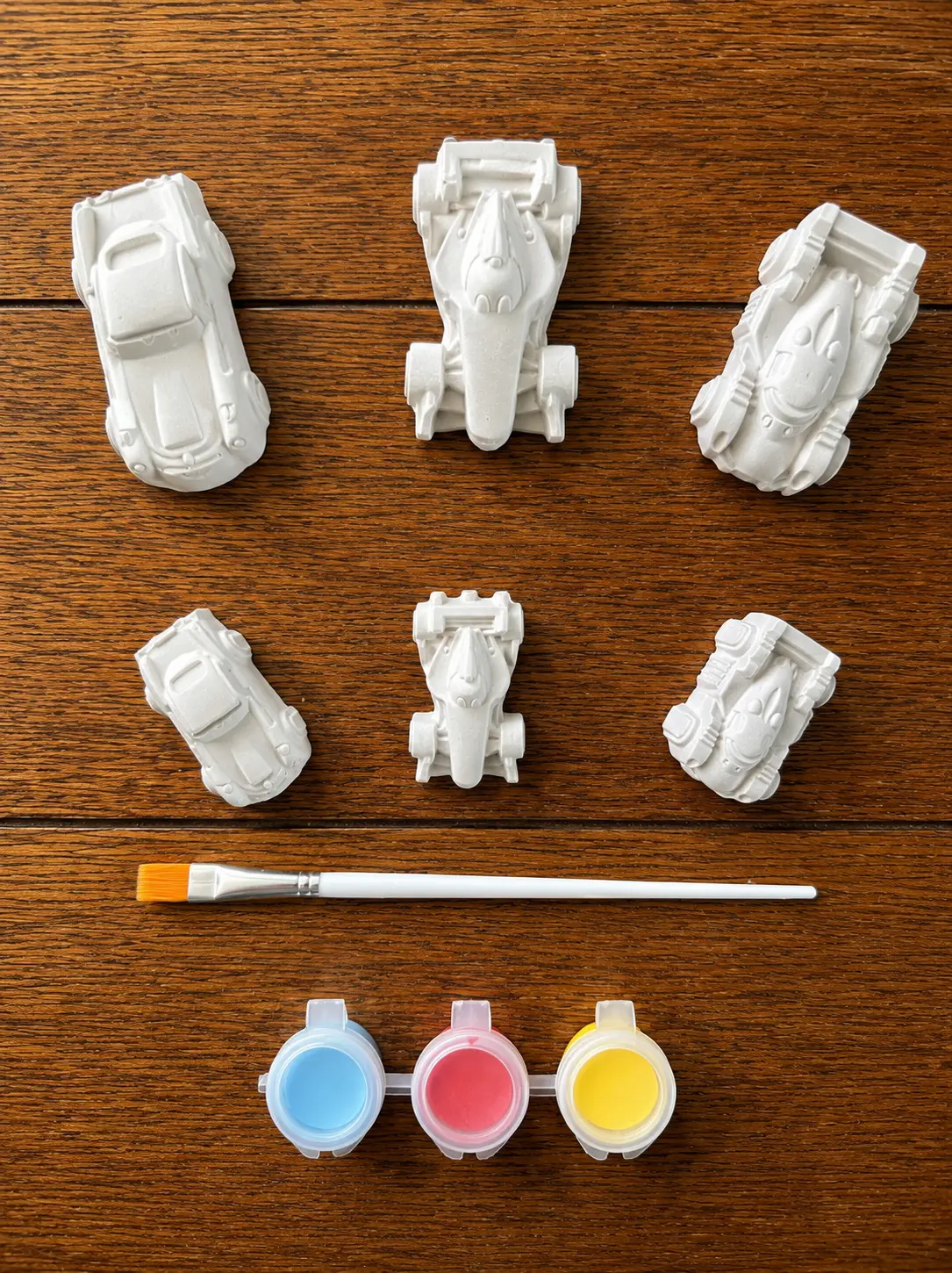 Six plaster car figurines with paints and a brush from a JAME Studio kit
